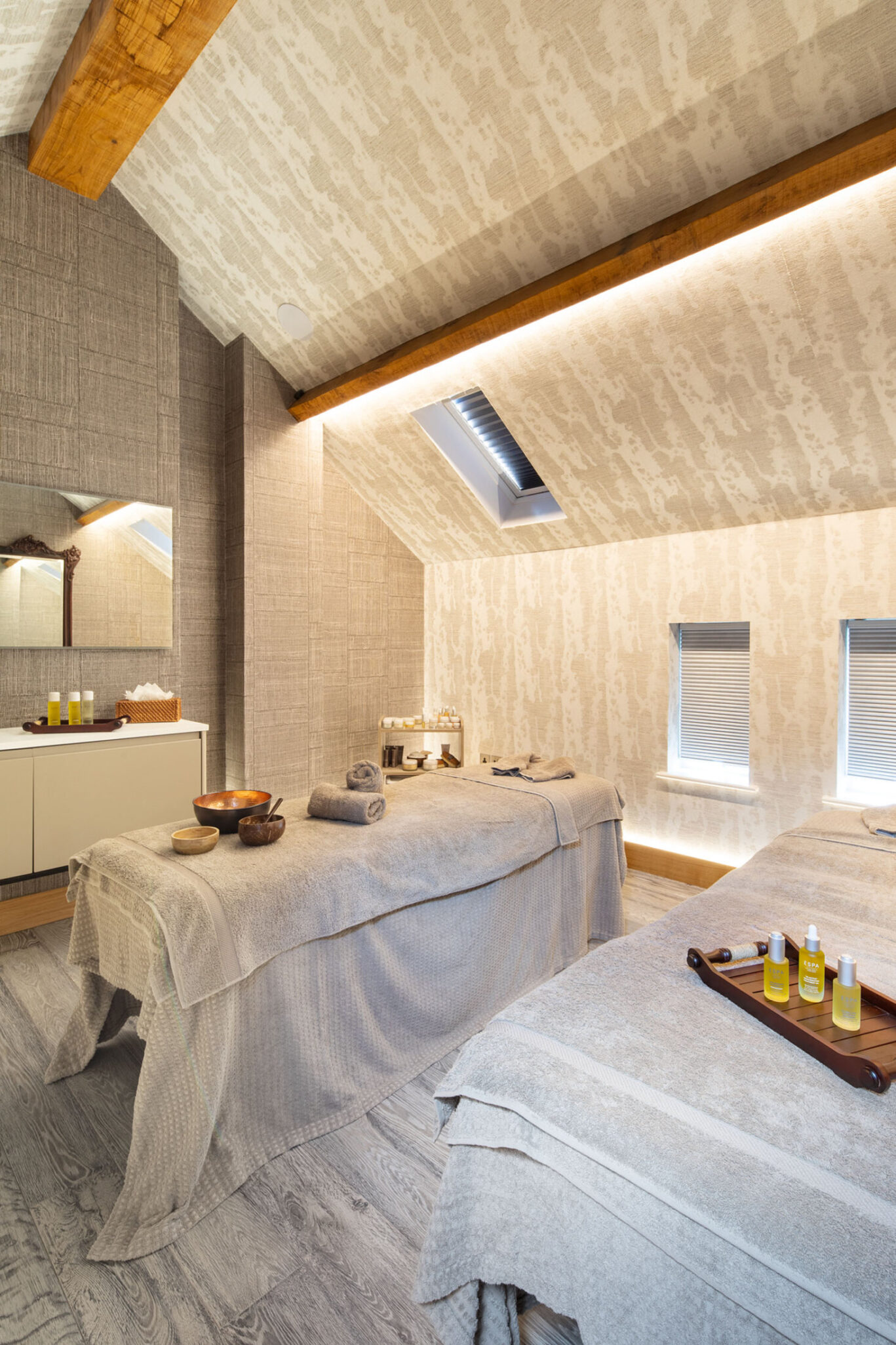Peaceful spa treatment room at Gilpin with two massage beds beneath a vaulted wooden ceiling.