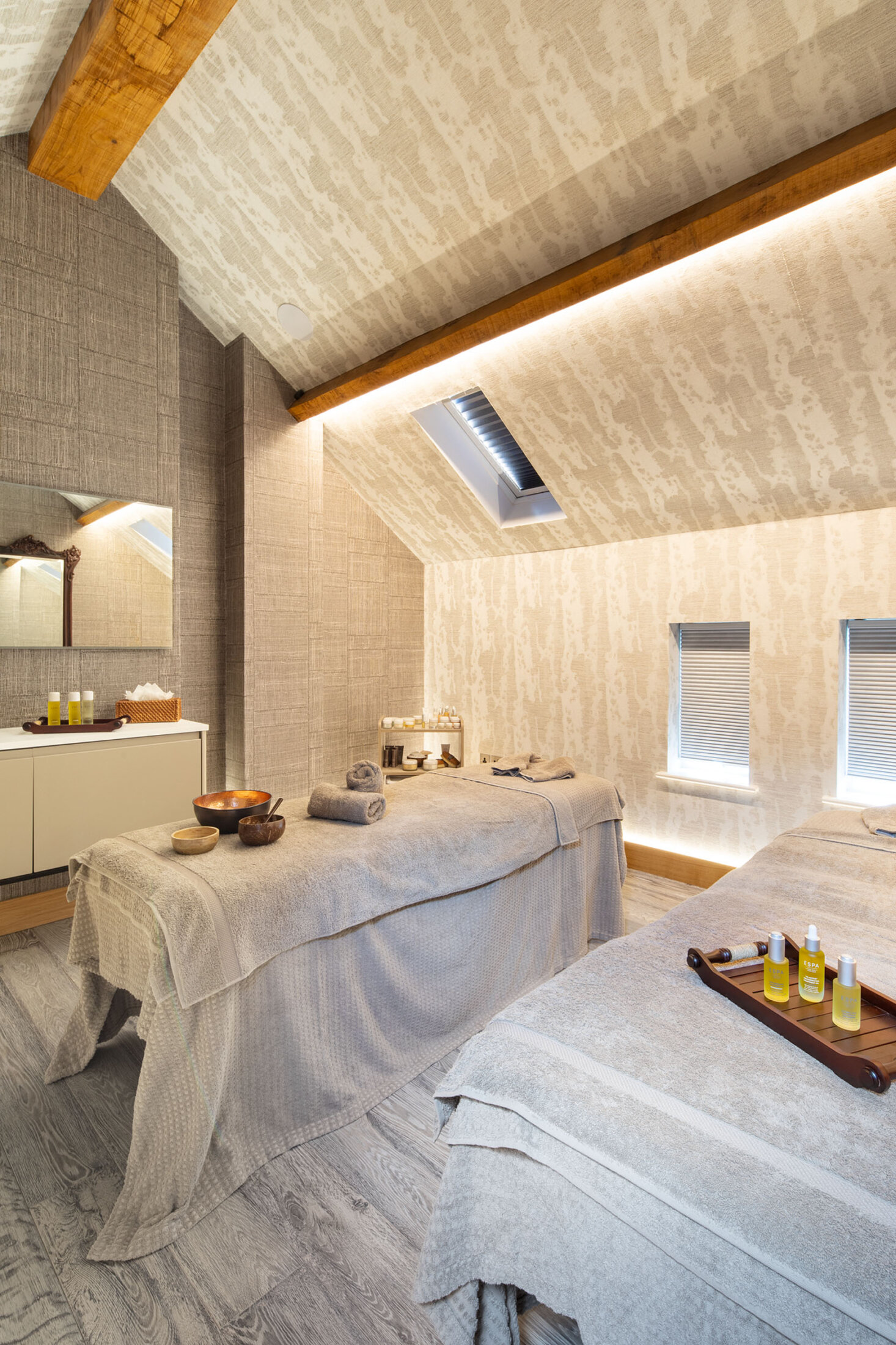 Peaceful spa treatment room at Gilpin with two massage beds beneath a vaulted wooden ceiling.