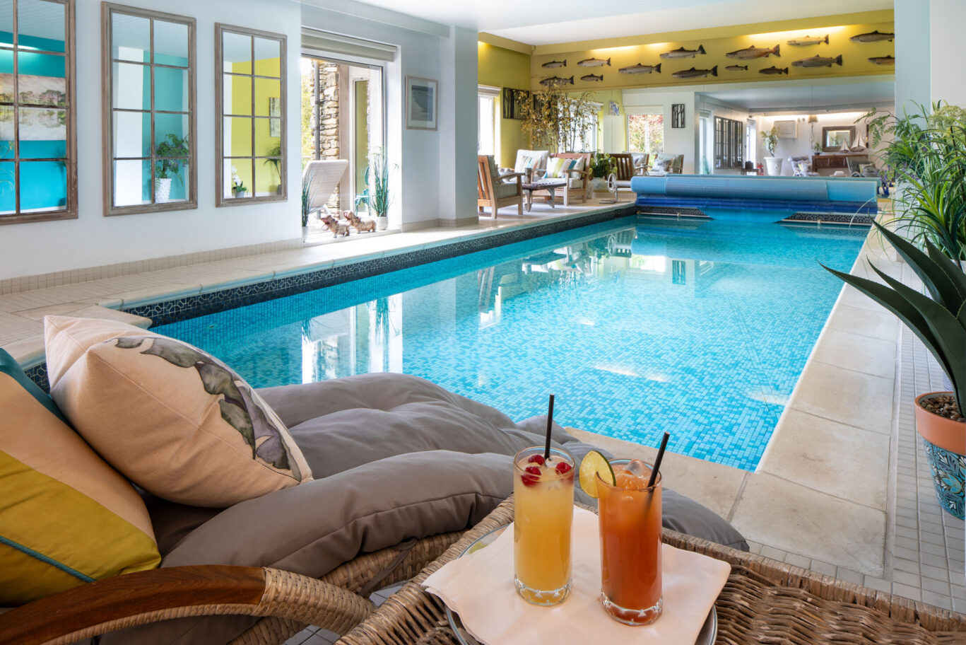 Indoor swimming pool at Gilpin Lake House, with comfortable poolside seating and drinks overlooking the water.
