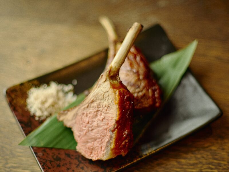 Gilpin Spice's lamb, sliced to reveal a pink centre, served on the bone with a crisp browned exterior on a ceramic plate.