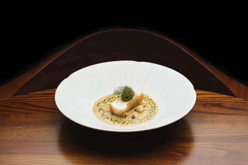 Monkfish dish at SOURCE, elegantly presented with a creamy sauce and delicate seasonal garnishes.