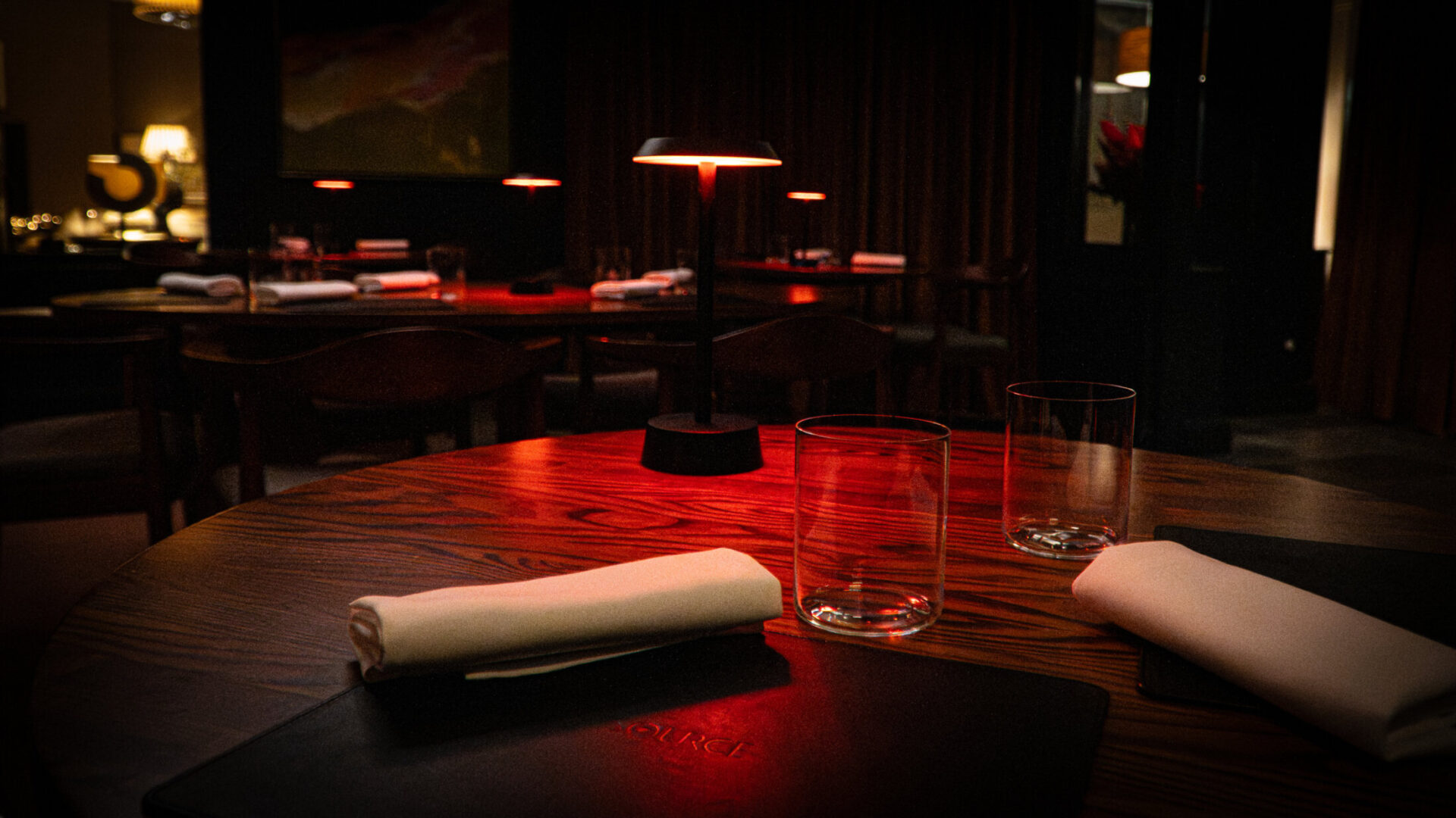 SOURCE dining room at Gilpin Hotel, with intimate tables illuminated by warm red lamps.