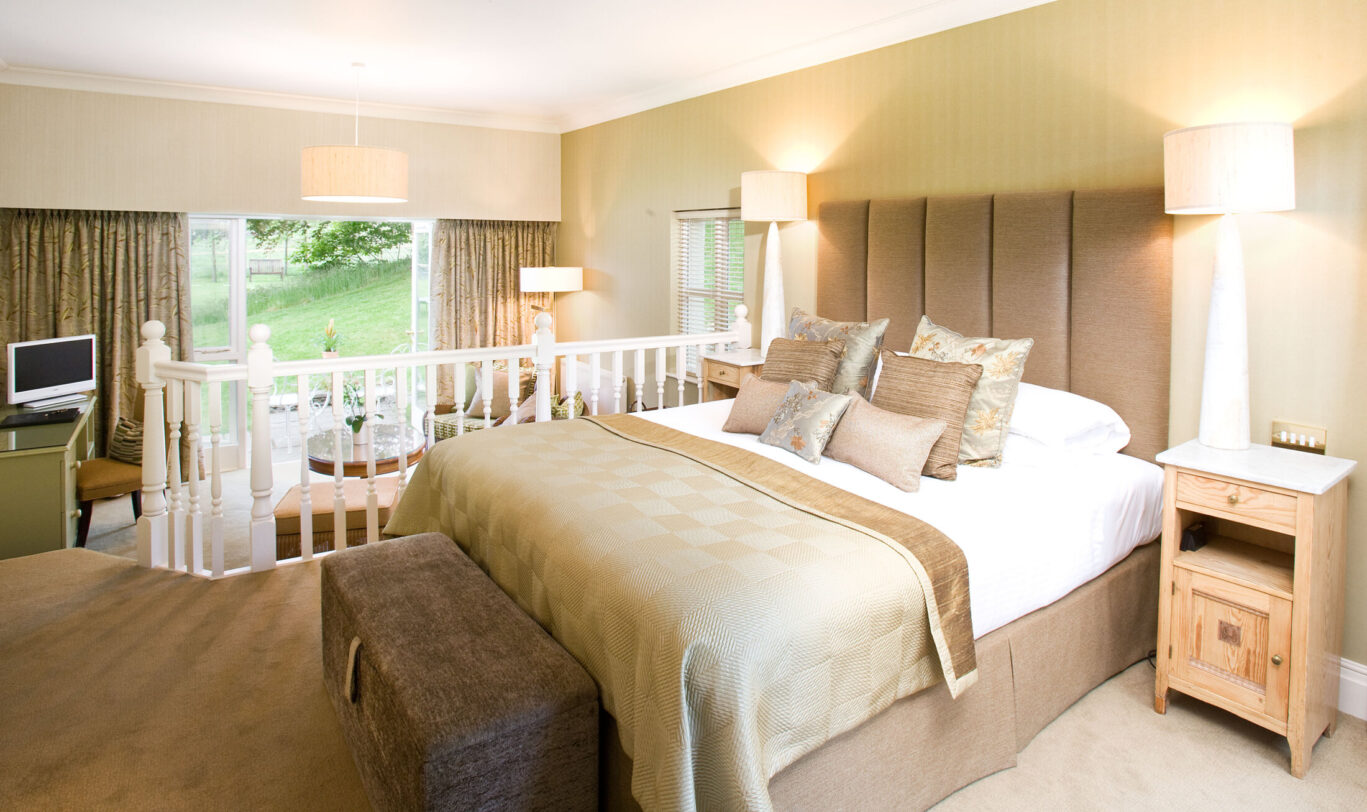 Spacious Junior Suite at Gilpin Hotel with a king-size bed and separate lounge area overlooking the gardens.
