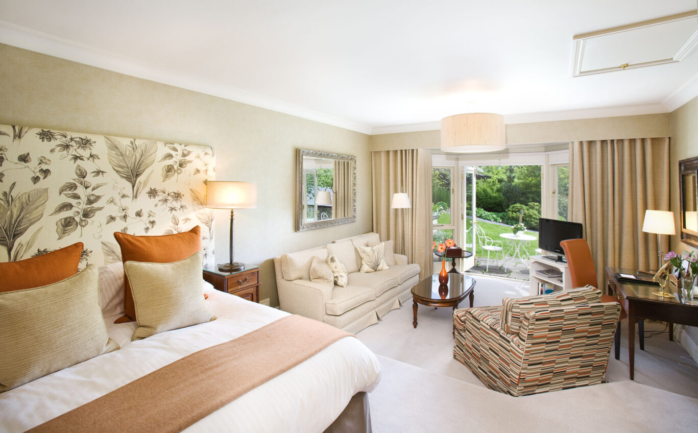 Junior Suite at Gilpin Hotel with a king-size bed, lounge seating and doors opening onto a private garden terrace.
