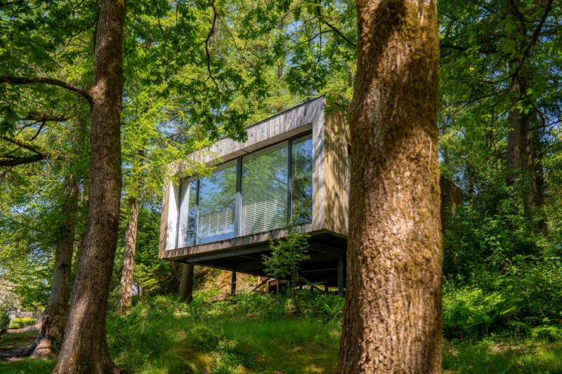 Gilpin Lake House Jetty Spa nestled among mature trees, with floor-to-ceiling windows overlooking the woodland.