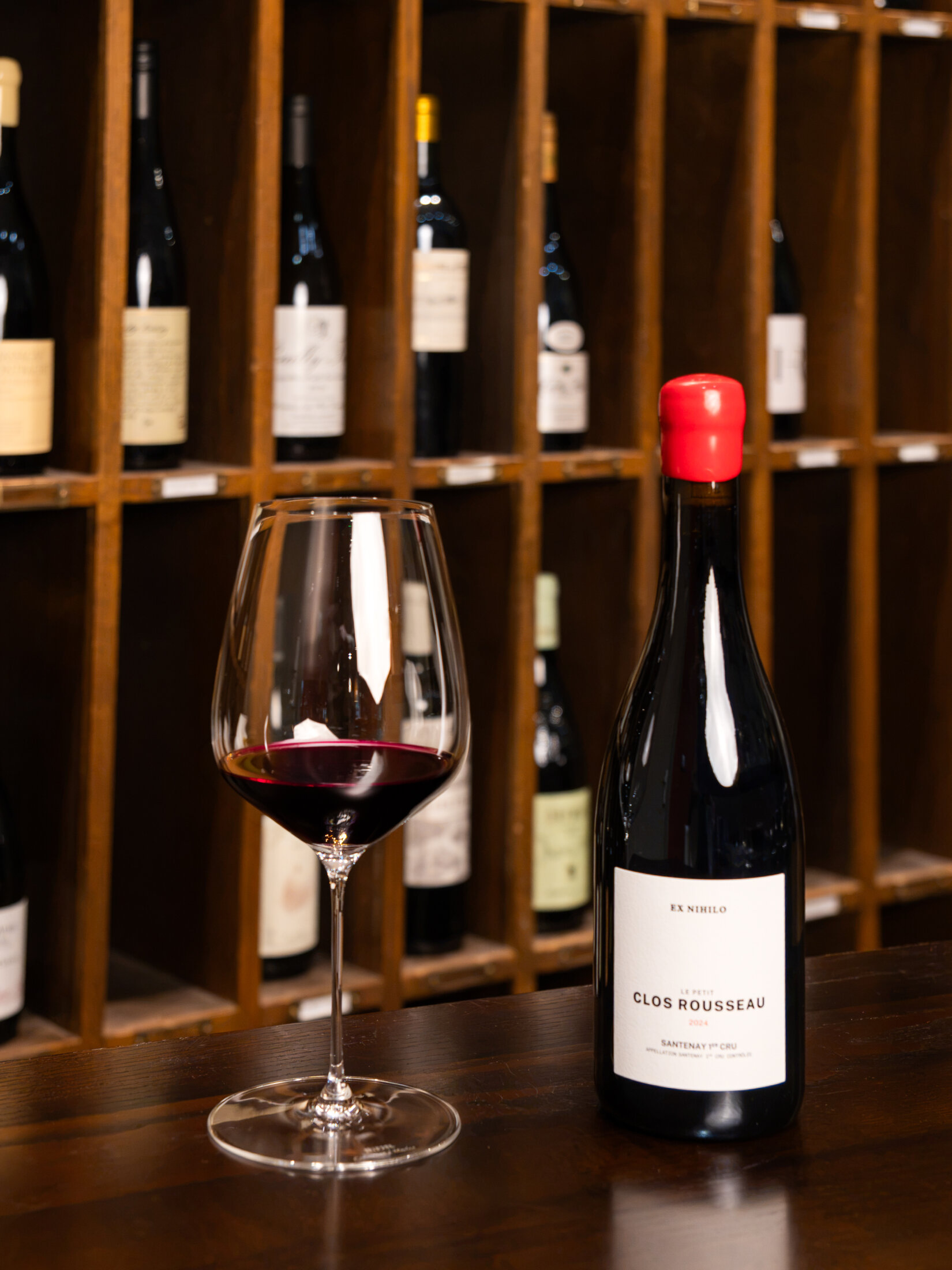 Bottle and glass of red wine displayed beside the wine cellar at SOURCE, Gilpin Hotel.
