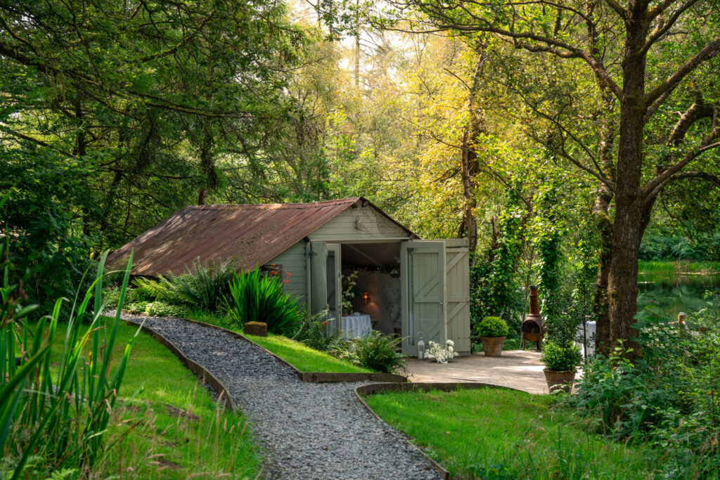 Lakeside boathouse at Gilpin Lake House, tucked among trees and greenery beside a gravel path.