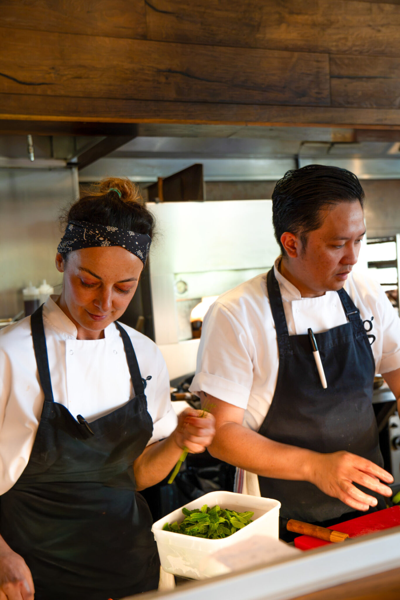 A woman and a man from the Gilpin Spice kitchen team preparing fresh ingredients together in the restaurant kitchen.
