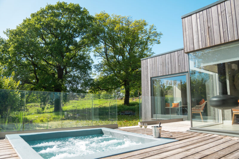 Gilpin Spa Suite exterior with a private outdoor hot tub, wooden terrace and views across the surrounding gardens.