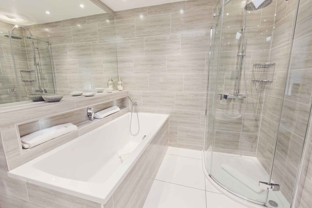 Kentmere Junior Suite bathroom at Gilpin Hotel with a large bath, walk-in rainfall shower and contemporary grey tiled finishes.