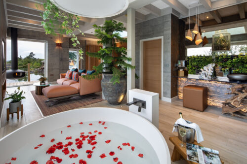 Luxury Gilpin Spa Suite bathroom with a freestanding bath filled with rose petals and an open-plan lounge overlooking the gardens.
