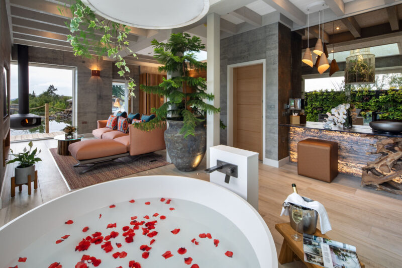 Luxury Gilpin Spa Suite bathroom with a freestanding bath filled with rose petals and an open-plan lounge overlooking the gardens.