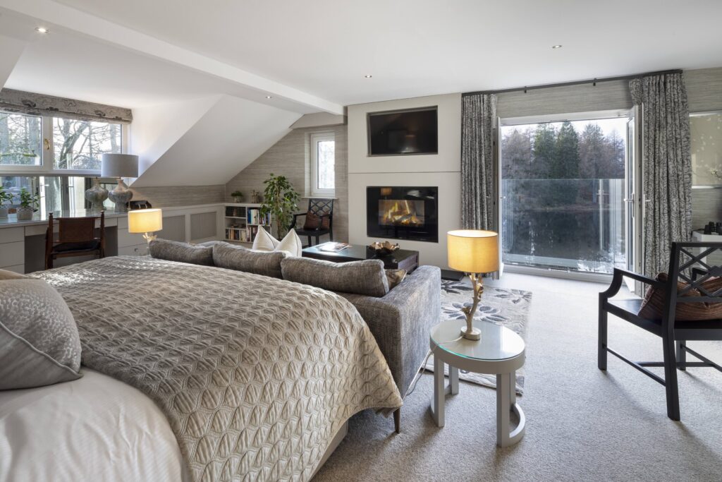 Maud Room at Gilpin Lake House with a king-size bed, spacious seating area, fireplace and large windows overlooking the grounds.
