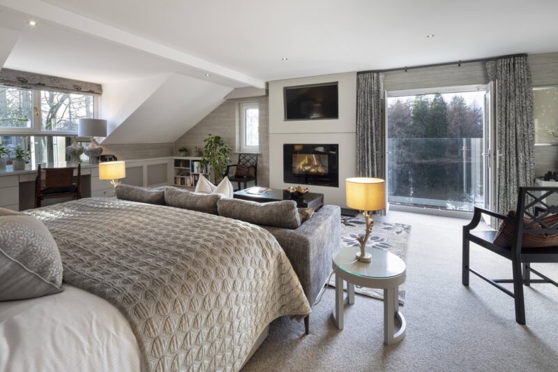 Maud Room at Gilpin Lake House with a king-size bed, spacious seating area, fireplace and large windows overlooking the grounds.