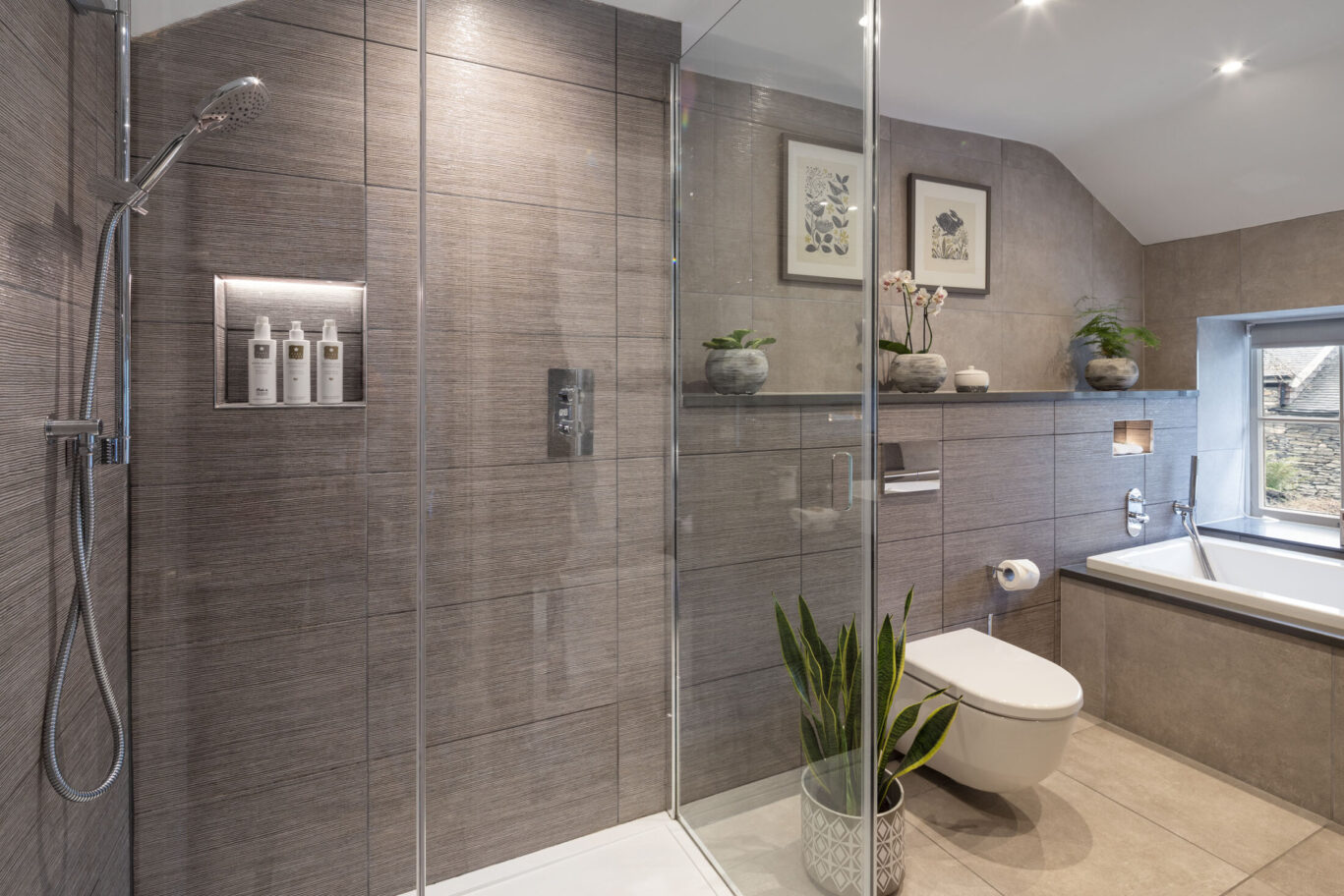 Cleabarrow Master Room bathroom at Gilpin Hotel with a walk-in shower, large bath and contemporary grey tiled finishes.