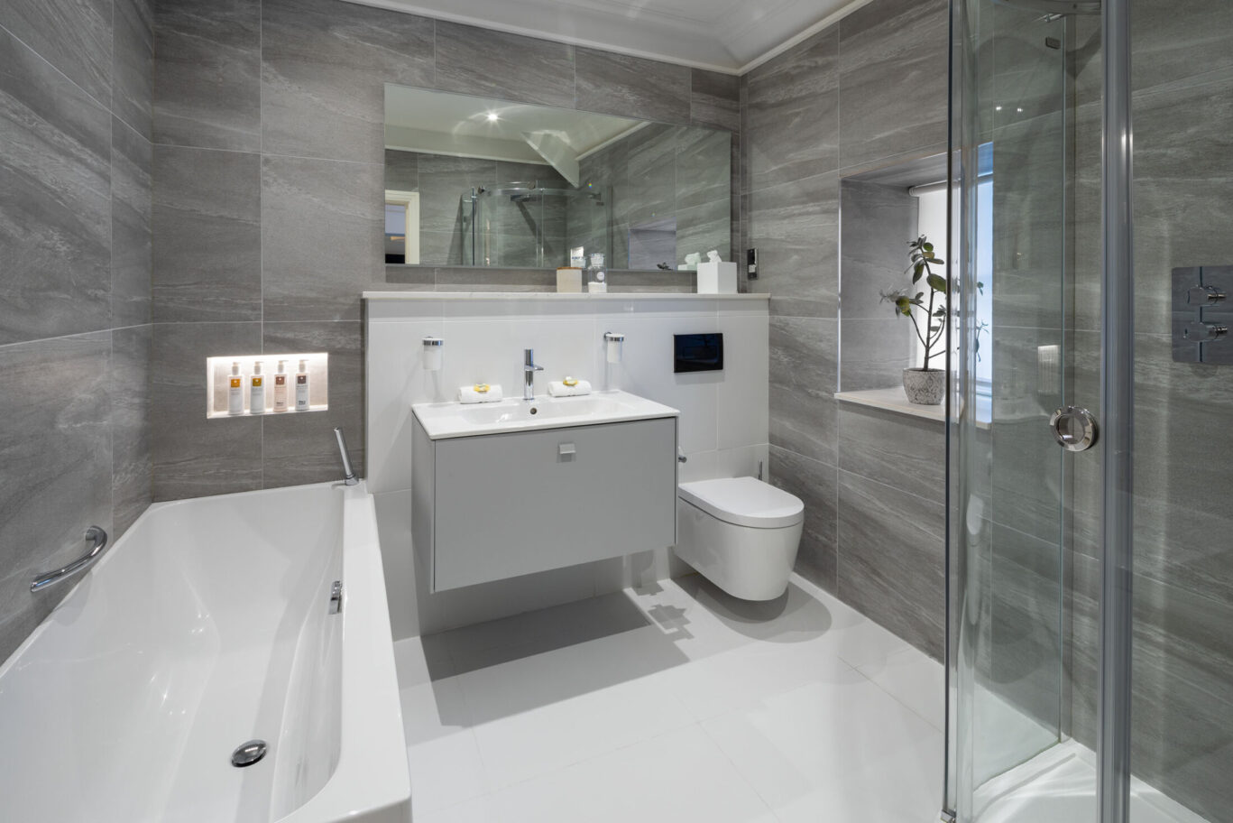 Crosthwaite Master Room bathroom at Gilpin Hotel with a large bath, walk-in shower, modern vanity and grey stone finishes.