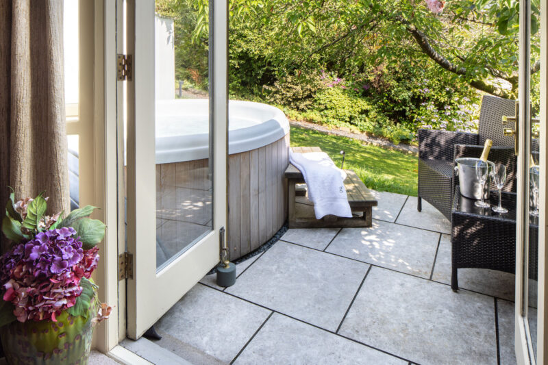 Grasmere Junior Suite at Gilpin Hotel with a private garden terrace, outdoor hot tub, seating and champagne.