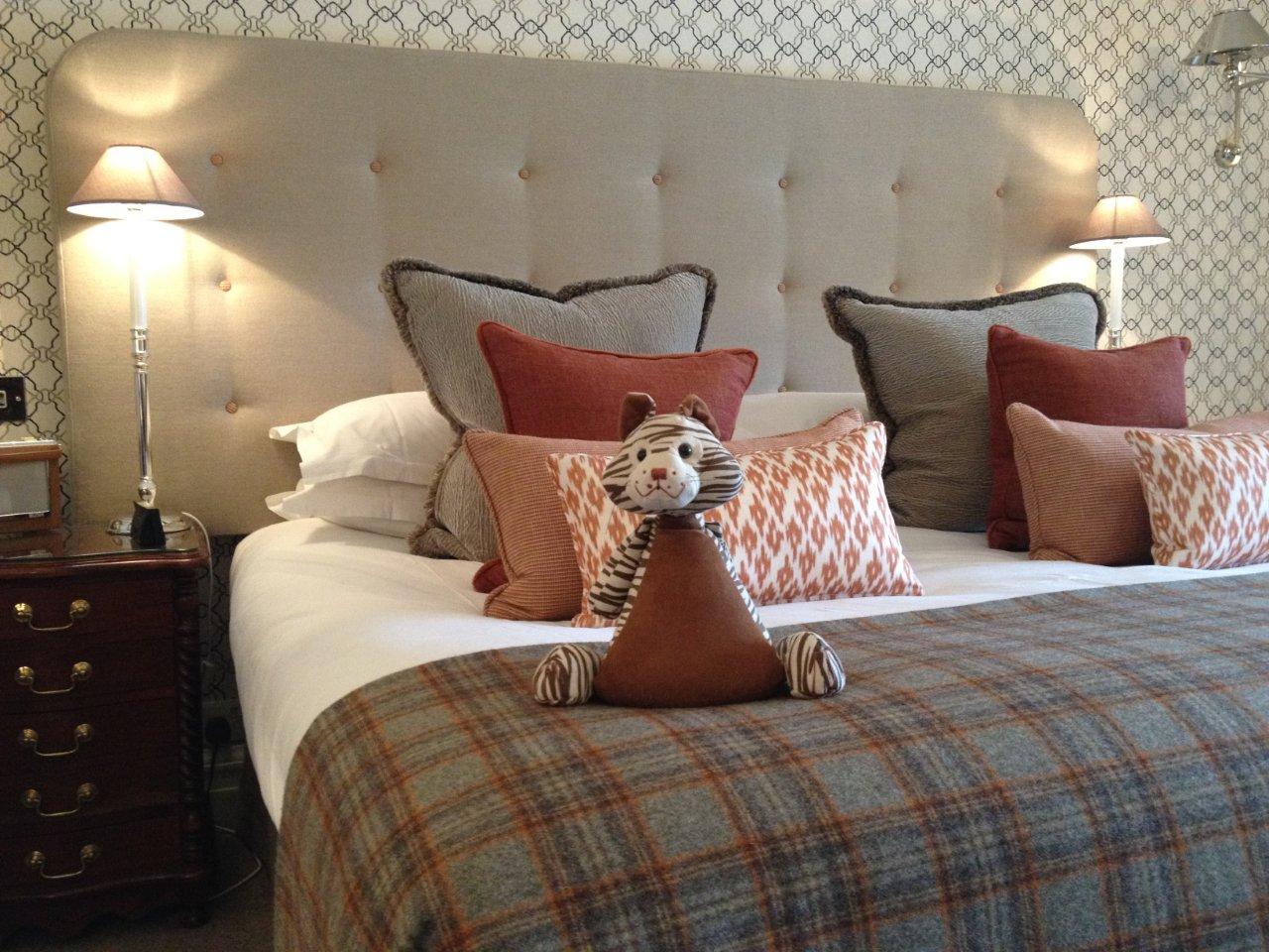Master Room at Gilpin Hotel with a king-size bed, patterned décor, warm bedside lighting and colourful cushions.