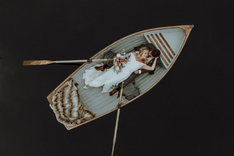 Bride and groom relaxing together in a rowing boat on the lake at Gilpin Lake House after their wedding.