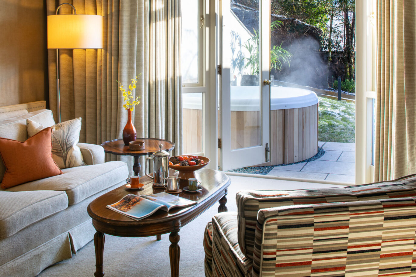 Junior Suite at Gilpin Hotel with comfortable lounge seating and open doors overlooking a private outdoor hot tub.