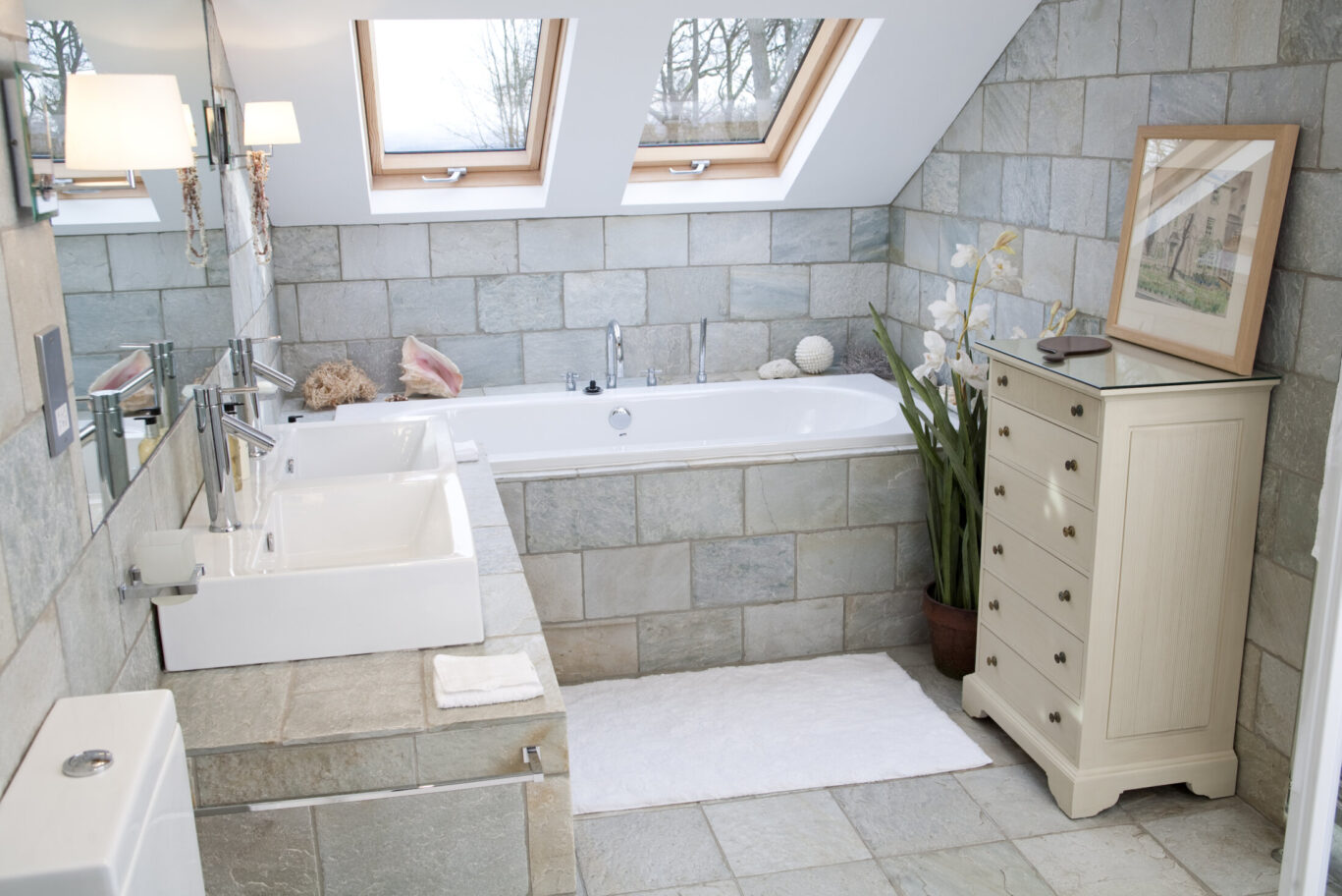 Spacious bathroom at Gilpin Lake House with a large tiled bath, twin sinks and skylights.