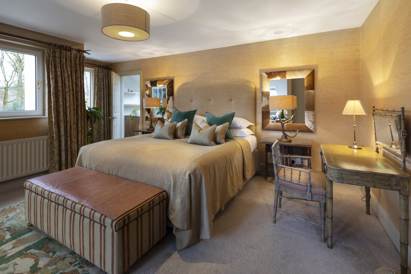 Bedroom at Gilpin Lake House with a king-size bed, warm neutral décor, writing desk and woodland views.