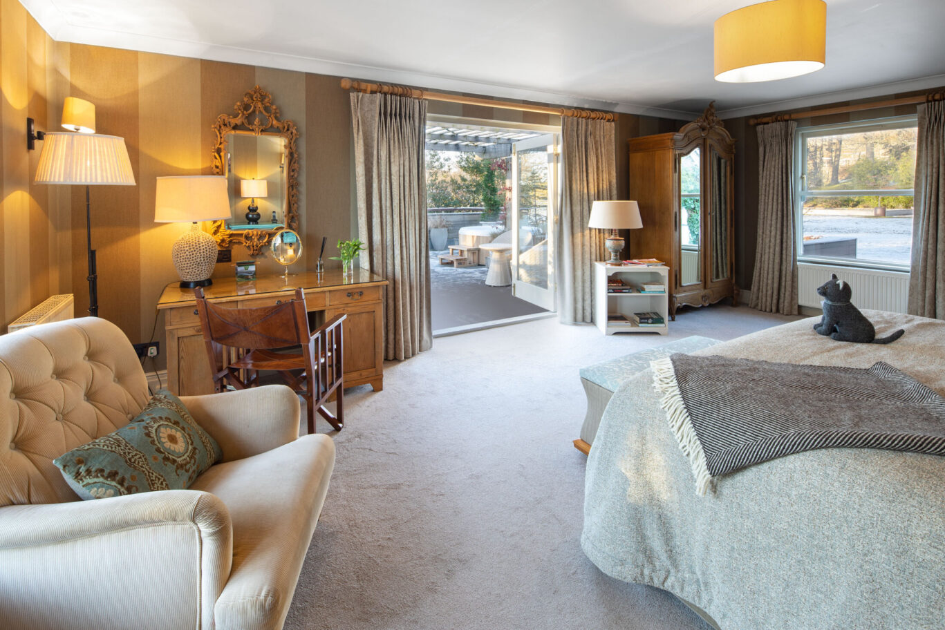 Junior Suite at Gilpin Hotel with a writing desk and open doors leading to a private terrace and outdoor hot tub.