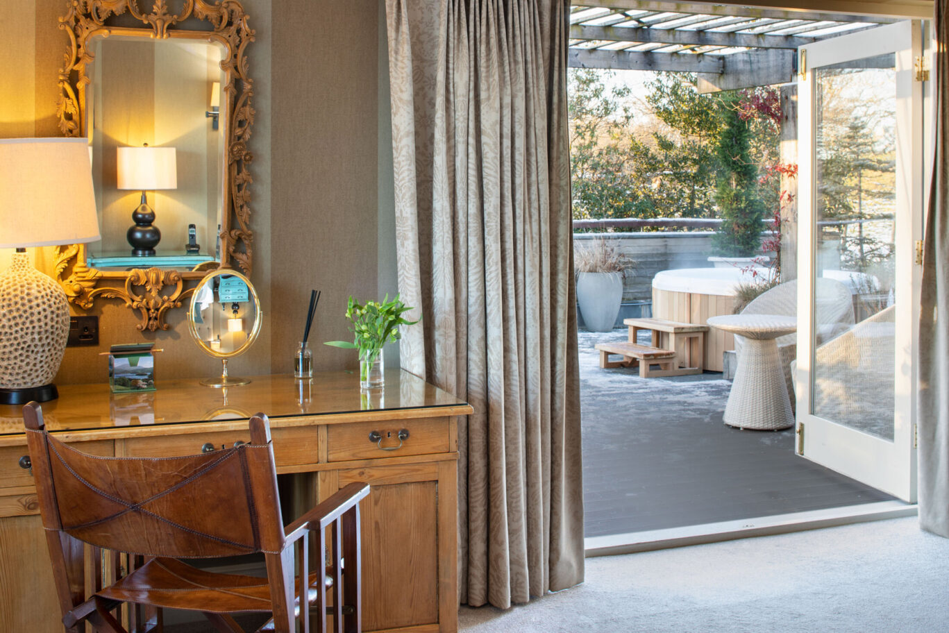 Junior Suite at Gilpin Hotel with a writing desk and open doors leading to a private terrace and outdoor hot tub.