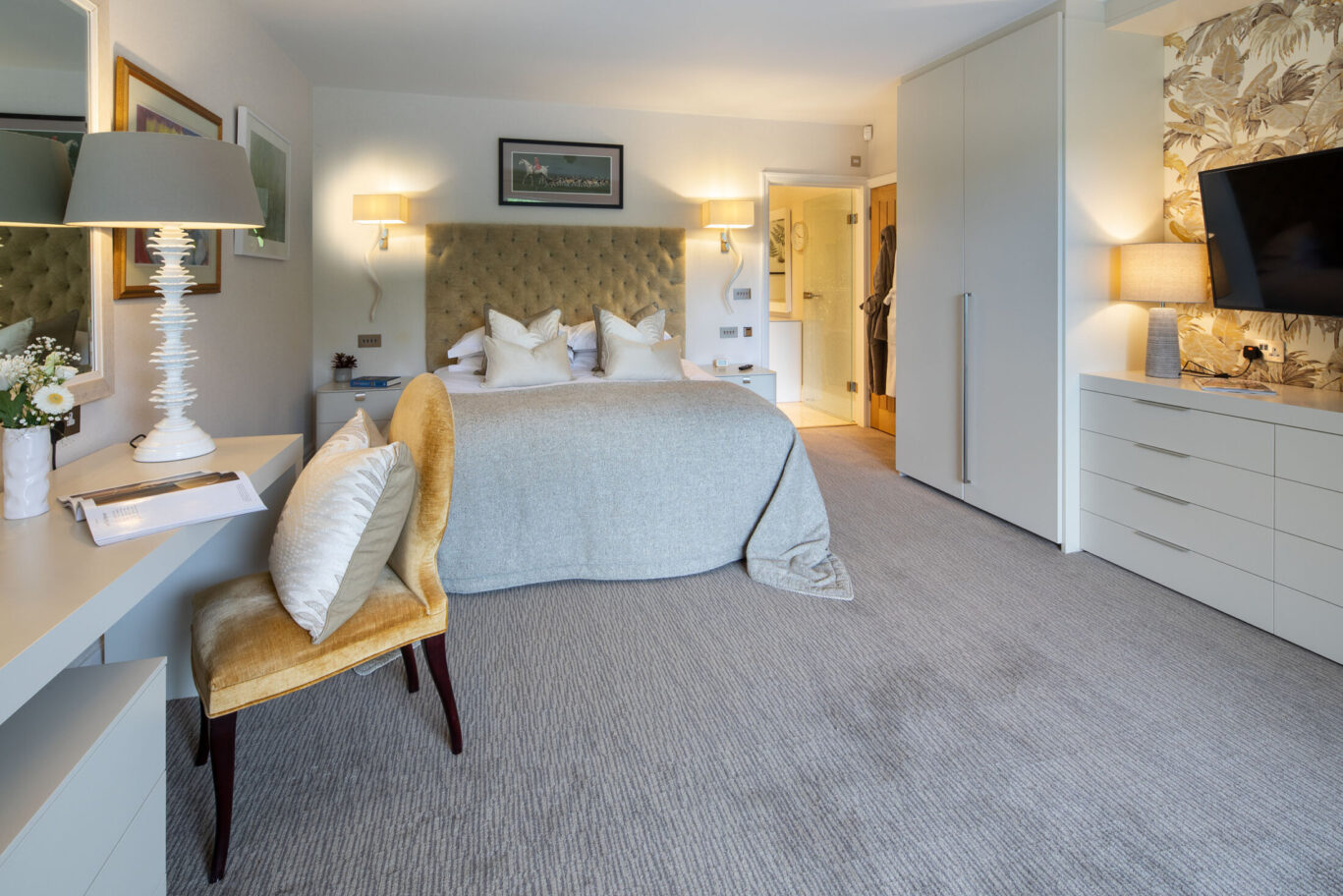 Spa Suite bedroom at Gilpin Lake House with a king-size bed, soft neutral furnishings, dressing table and contemporary stone feature wall.
