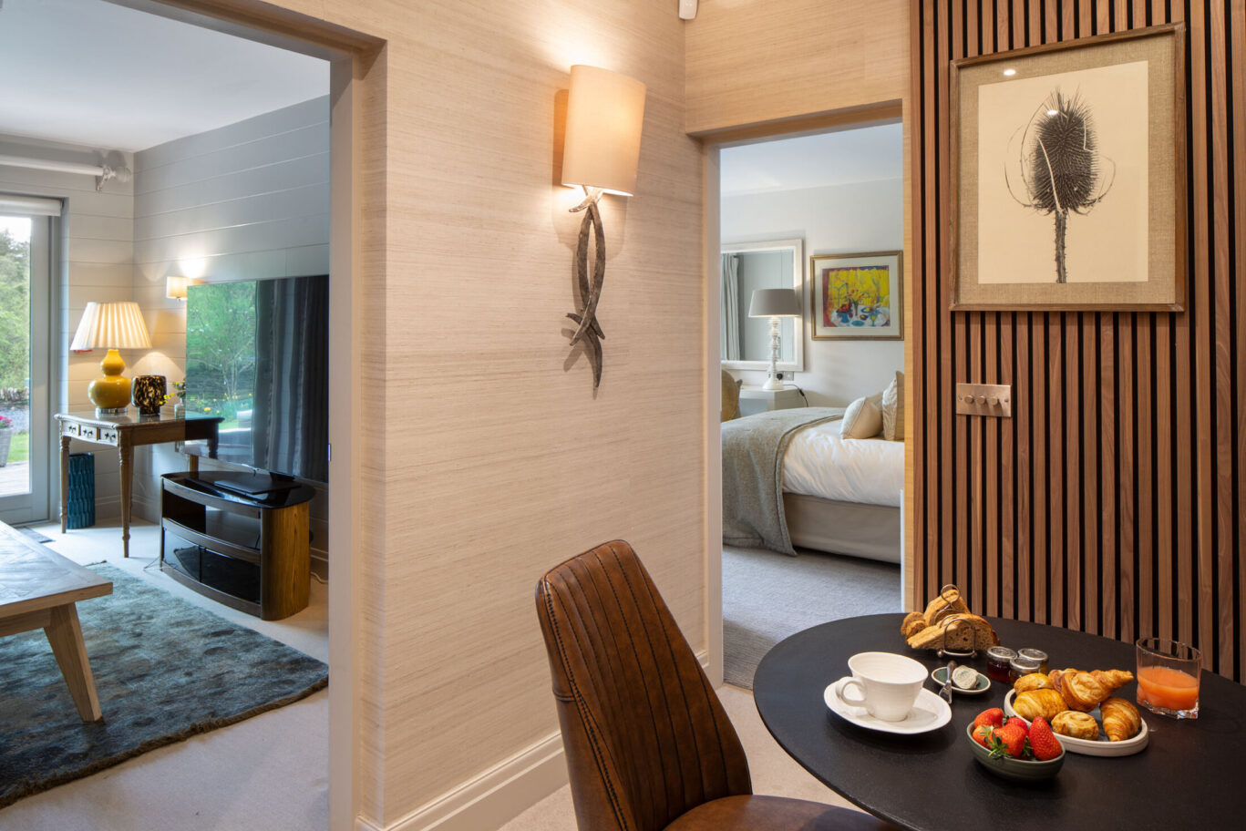 Spa Suite at Gilpin Lake House with a breakfast table set with pastries, fruit and coffee, leading through to the lounge and bedroom.