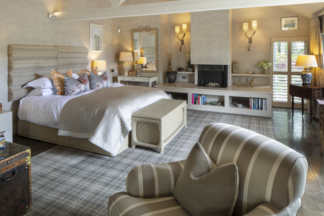 Luxury bedroom at Gilpin Lake House with a king-size bed, fireplace, comfortable seating and warm neutral décor.