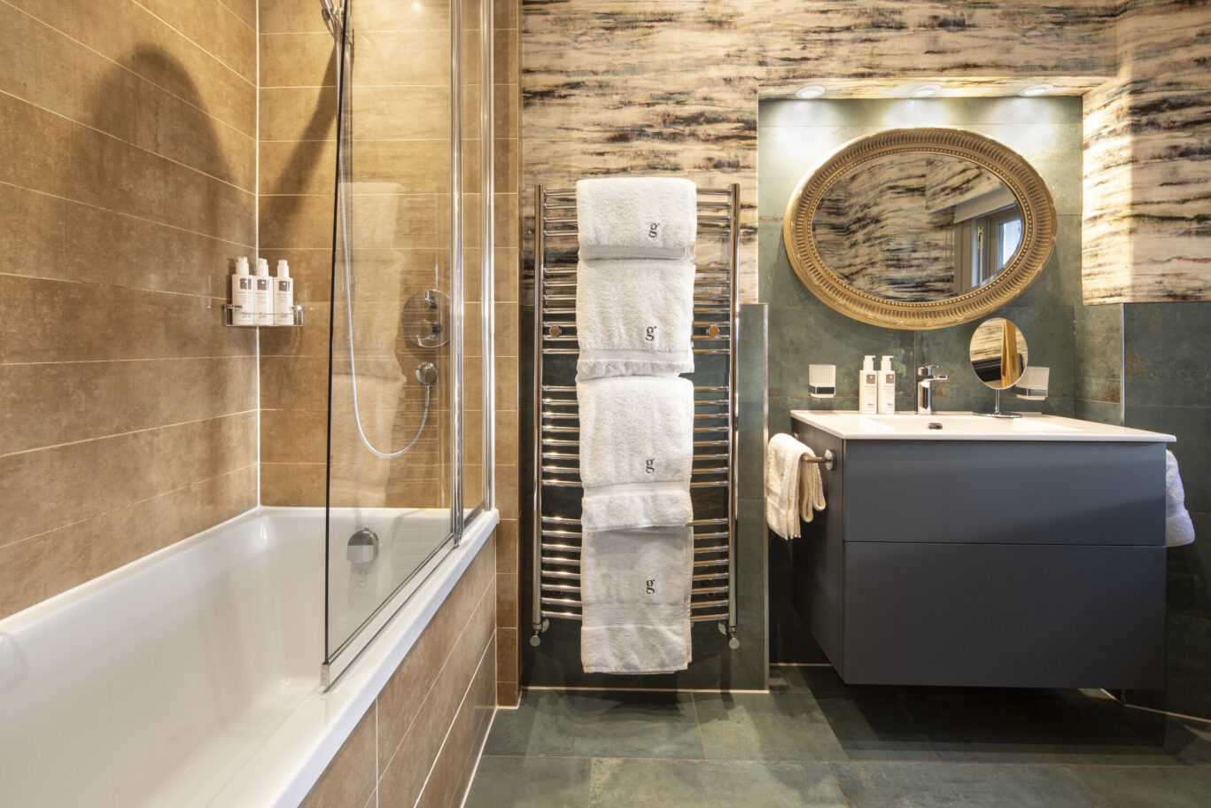 Winster Master Room bathroom at Gilpin Hotel with a bath and shower, contemporary vanity, heated towel rail and decorative tiled finishes.