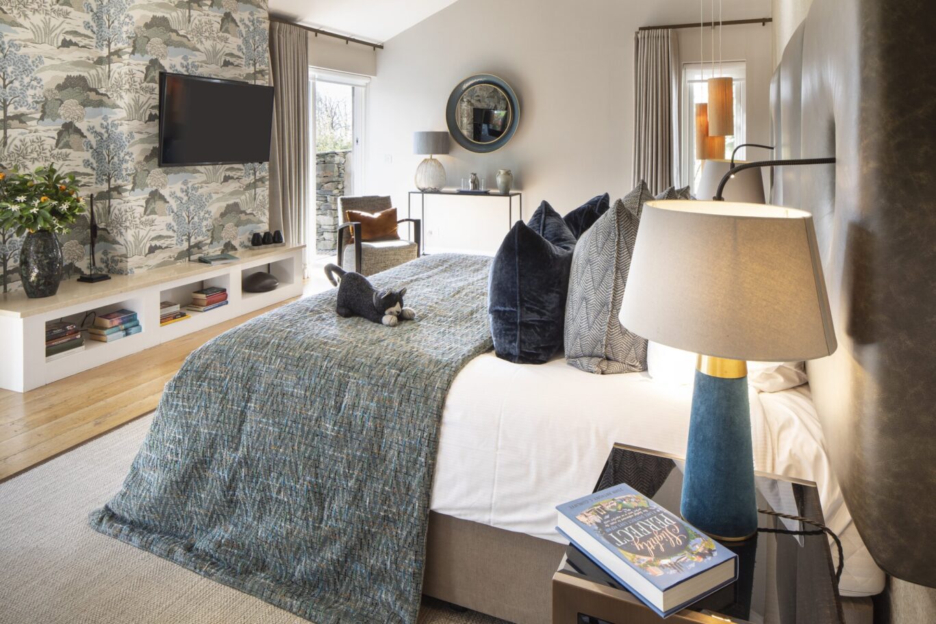Gilpin Hotel bedroom with a stone feature wall, king-size bed and contemporary furnishings.