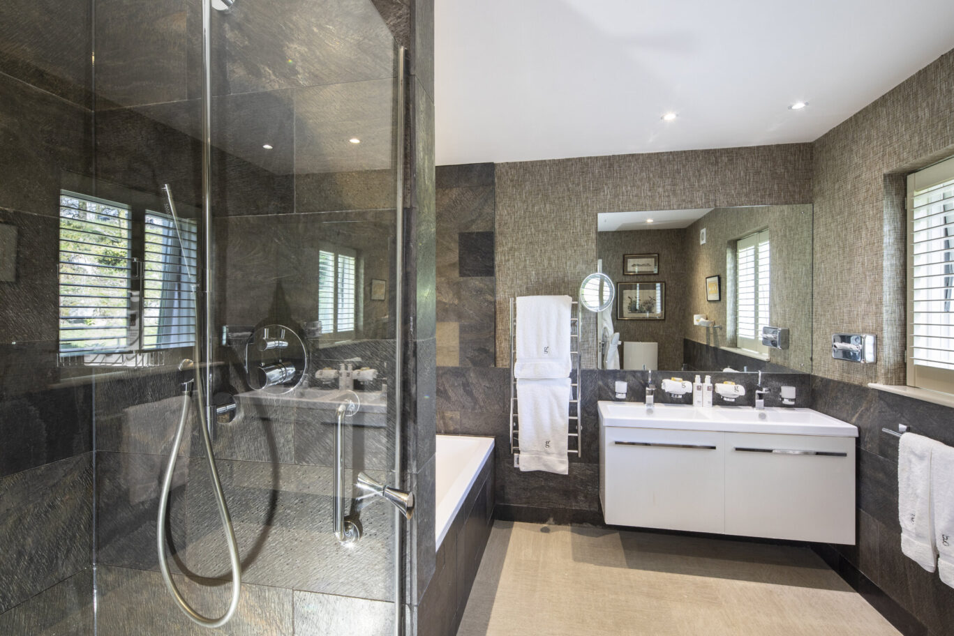 Modern bathroom at Gilpin Lake House with a walk-in rainfall shower, double vanity and contemporary stone finishes.