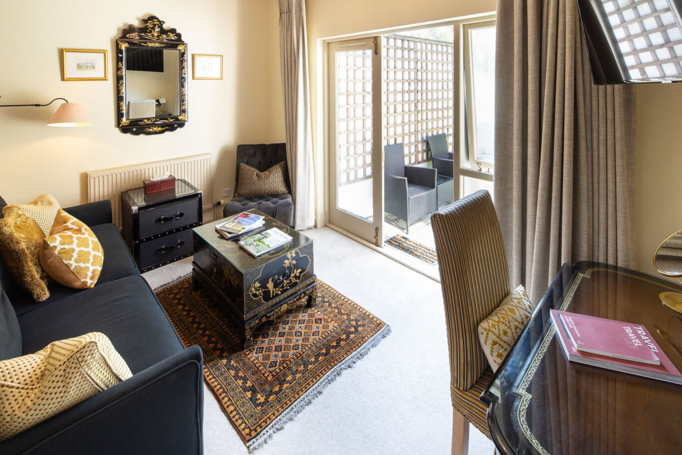 Junior Suite at Gilpin Hotel with a cosy lounge, writing desk and doors opening onto a private outdoor seating area.