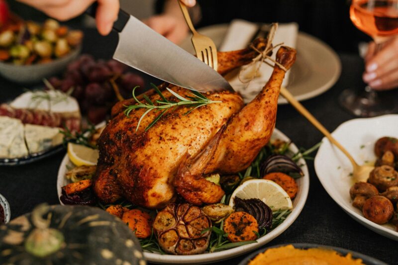 Roast chicken with rosemary, garlic, lemon and seasonal vegetables being carved at a festive dining table