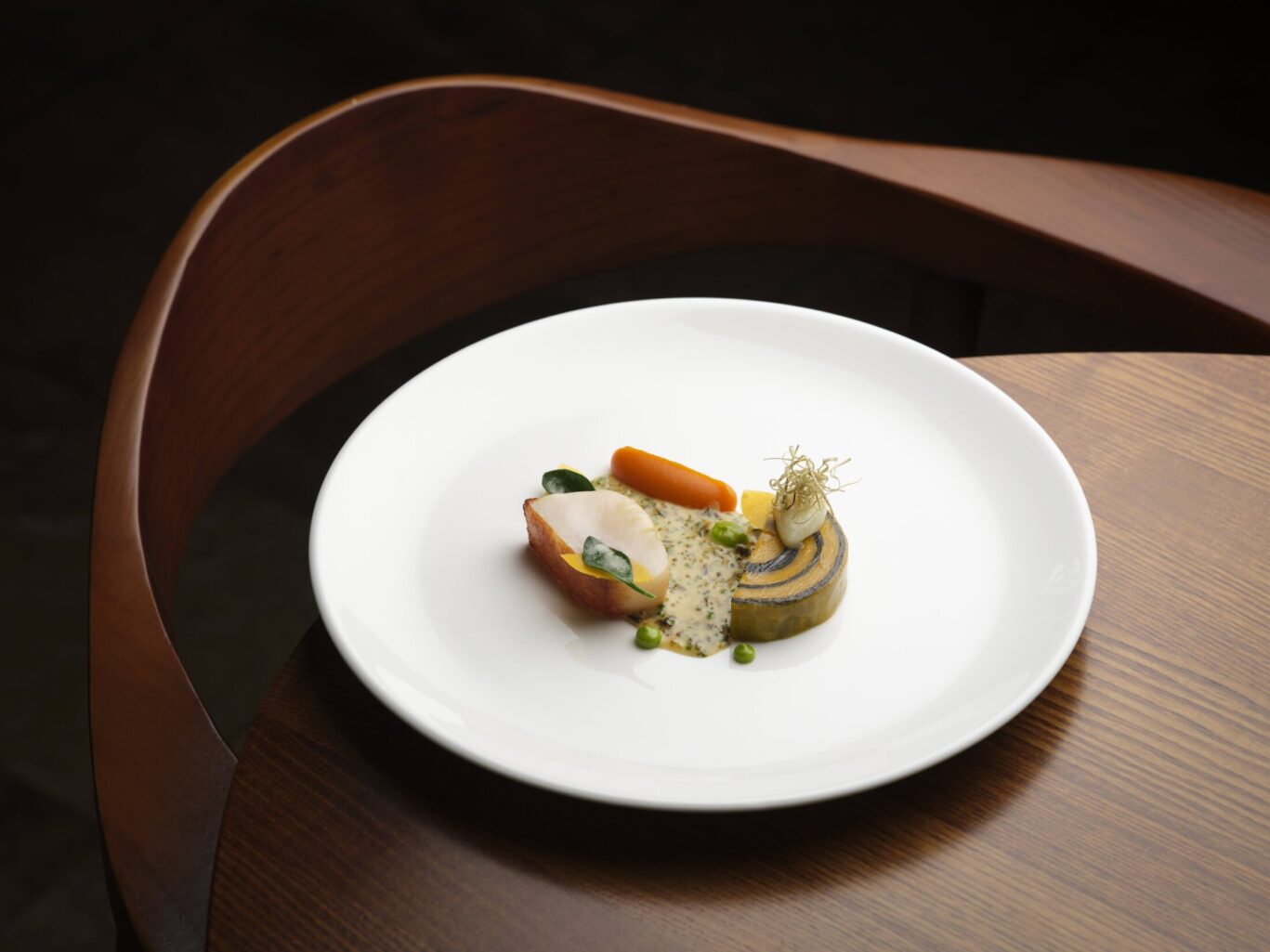 SOURCE at Gilpin Hotel's scallop dish, served with layered vegetables, a creamy herb sauce, vegetable purée and delicate garnish on a white plate.