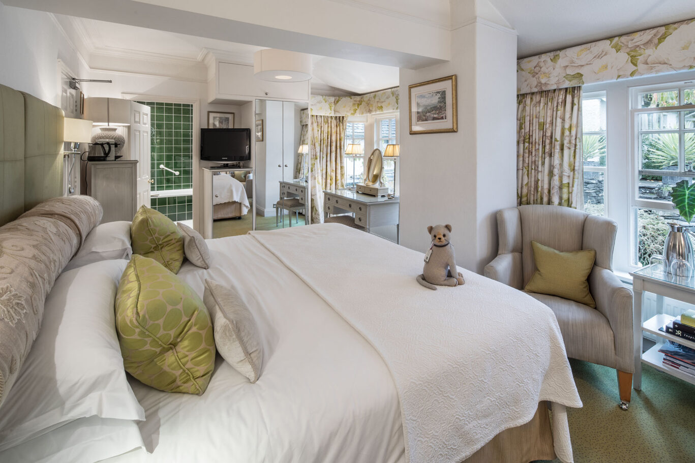 Master Room at Gilpin Hotel with a king-size bed, soft green furnishings and French doors opening onto the garden.